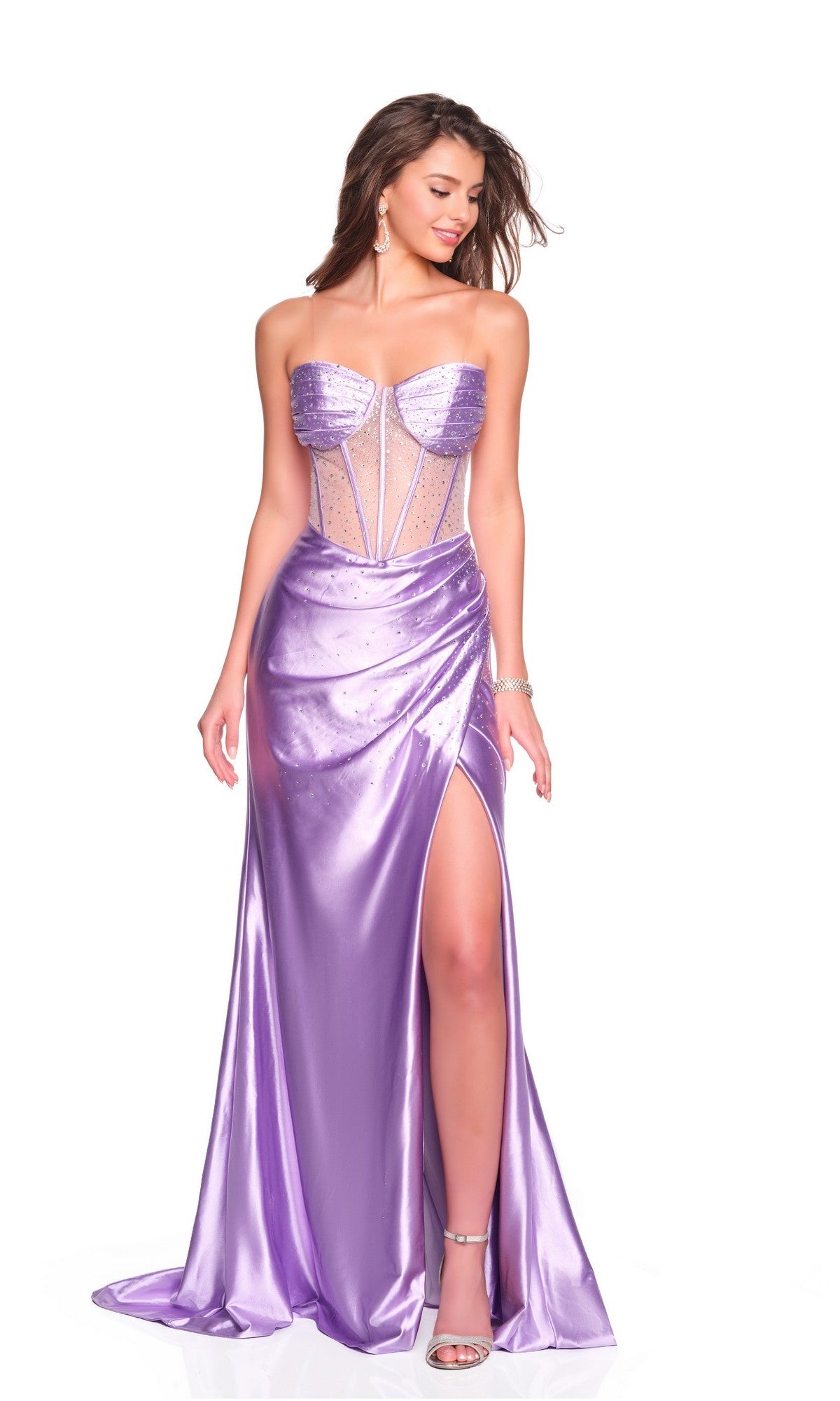 A woman stands against a white background wearing the Dave and Johnny 12477 long prom dress in lilac satin, featuring rhinestone embellishments, a strapless sheer corset bodice, and a thigh-high slit.
